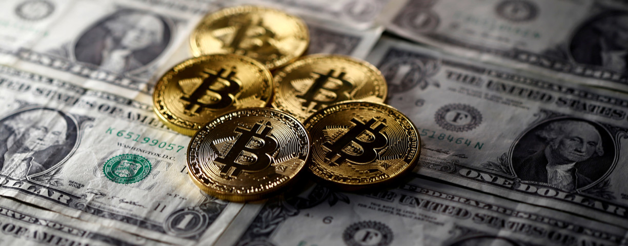 Bitcoin (virtual currency) coins placed on Dollar banknotes