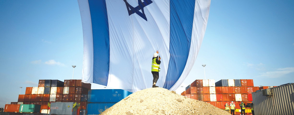 A WORKER at Ashdod port coordinates a crane to hang a giant Israeli national flag.