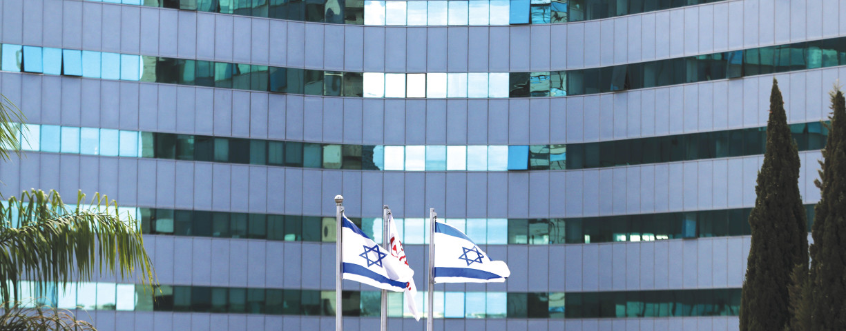 Israeli national flags flutter in front of an office tower at a business park housing high tech companies, at Ofer Park in Petah Tikva.