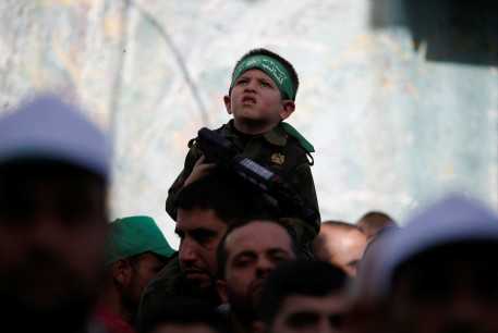  A boy holds a toy weapon as Palestinians take part in a rally marking the 34th anniversary of Hamas' founding, in the northern Gaza Strip December 10, 2021. 