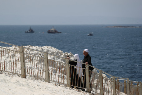  : People walk as Israeli navy boats are seen in the Mediterranean Sea as seen from Rosh Hanikra, close to the Lebanese border, northern Israel May 4, 2021. 