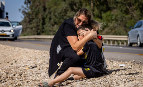 A woman and child take cover as a siren sounds a warning of incoming rockets fired from the Gaza strip on a road between Ashkelon and Sderot, southern Israel, on May 19, 2021.
