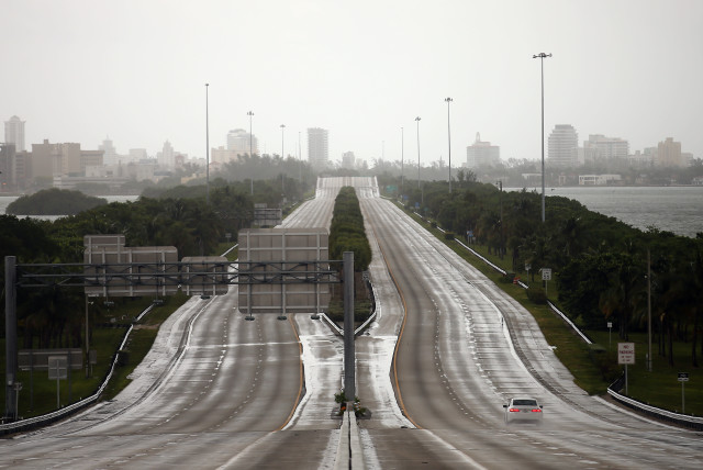 A car drives along an empty highway in Miami before the arrival of Hurricane Irma in south Florida (photo credit: CARLOS BARRIA / REUTERS)