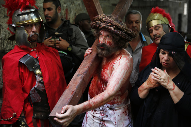 イエスの役割を果たしている男は、エルサレムの旧市街April18、2014で、聖週間の間に聖金曜日にDolorosa経由に沿って行列の間に十字架を運びます。 （写真クレジット: フィンバール-オライリー／ロイター）
