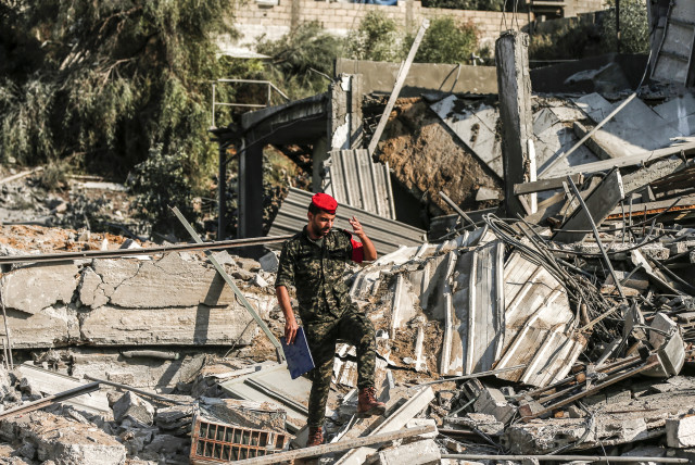 A member of Hamas' military police walks through rubble at a site that was hit by Israeli air strikes in Gaza City on August 9, 2018 (photo credit: MAHMUD HAMS / AFP)