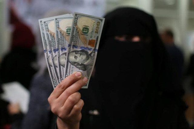 A Palestinian Hamas-hired civil servant displays U.S. Dollar banknotes after receiving her salary paid by Qatar, in Khan Younis in the southern Gaza Strip December 7, 2018. (photo credit: IBRAHEEM ABU MUSTAFA/REUTERS)