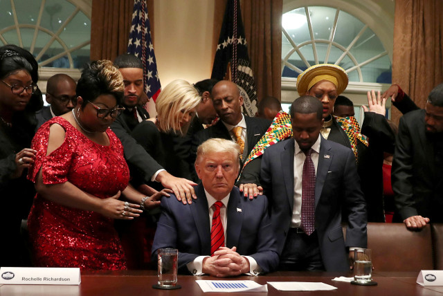 African-American supporters, including Terrence Williams, Angela Stanton and Diamond and Silk, pray with U.S. President Donald Trump in the Cabinet Room of the White House in Washington, US. (photo credit: REUTERS)