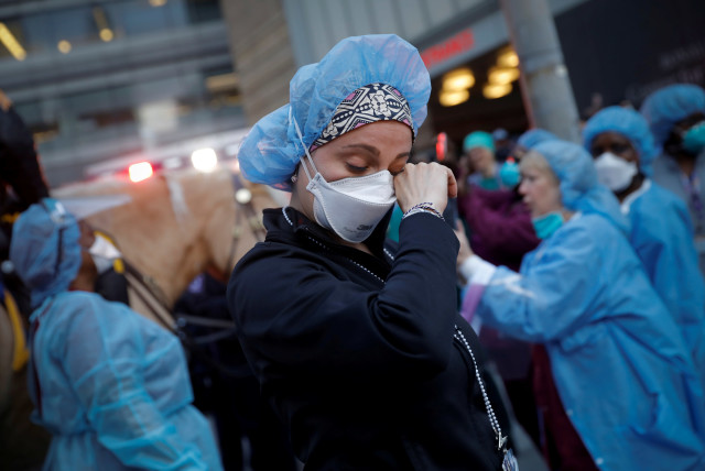A nurse wipes away tears as she stands outside NYU Langone Medical Center on 1st Avenue in Manhattan, U.S. April 16, 2020.  (photo credit: REUTERS/MIKE SEGAR)
