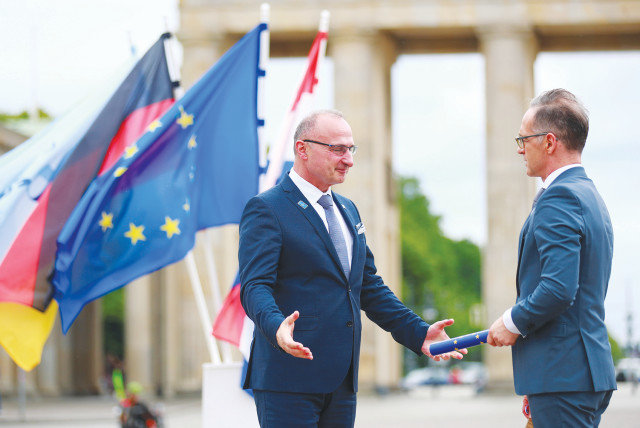 GERMAN FOREIGN Minister Heiko Maas (right) takes over the rotating presidency of the Council of the European Union from Croatian Foreign Minister Gordan Grlic-Radman during a symbolic handover in front of the Brandenburg Gate in Berlin last week.  (photo credit: HANNIBAL HANSCHKE/REUTERS)