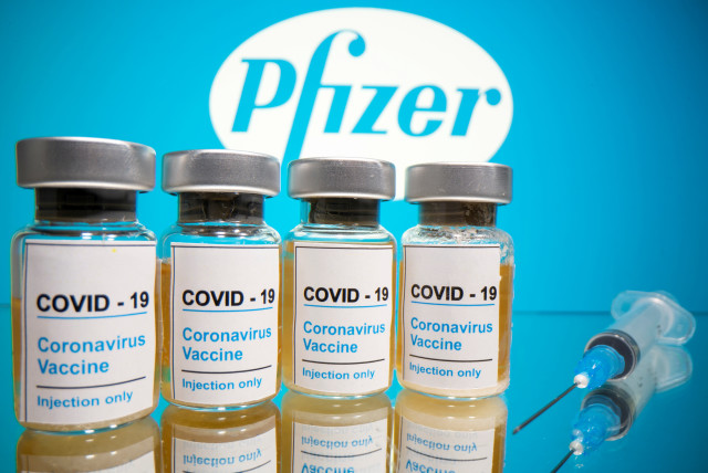 Vials with a sticker reading, "COVID-19 / Coronavirus vaccine / Injection only" and a medical syringe are seen in front of a displayed Pfizer logo in this illustration taken October 31, 2020 (photo credit: REUTERS/DADO RUVIC/ILLUSTRATION/FILE PHOTO)