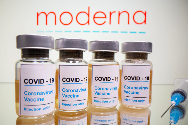 Vials with a sticker reading, "COVID-19 / Coronavirus vaccine / Injection only" and a medical syringe are seen in front of a displayed Moderna logo in this illustration taken October 31, 2020.  (photo credit: REUTERS)