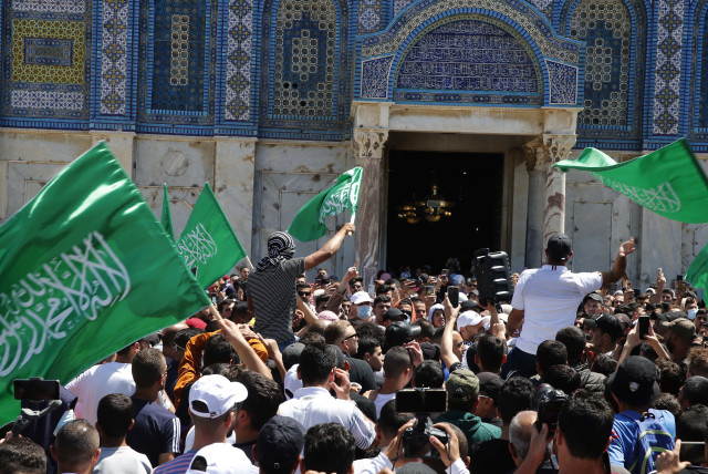 People hold Hamas flags as Palestinians gather after performing the last Friday of Ramadan to protest over the possible eviction of several Palestinian families from homes on land claimed by Jewish settlers in the East Jerusalem neighborhood of Sheikh Jarrah, May 7, 2021.  (photo credit: JAMAL AWAD/FLASH90)