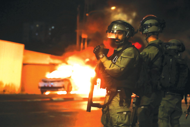 Αυτή είναι η εικόνα της νίκης της Χαμάς.  Οι αστυνομικοί στέκονται κοντά σε ένα φλεγόμενο αυτοκίνητο της αστυνομίας κατά τη διάρκεια συγκρούσεων με Αραβούς ταραχές στην αραβο-εβραϊκή πόλη Λοντ αυτήν την εβδομάδα.  (πιστωτική φωτογραφία: AMMAR AWAD / REUTERS)