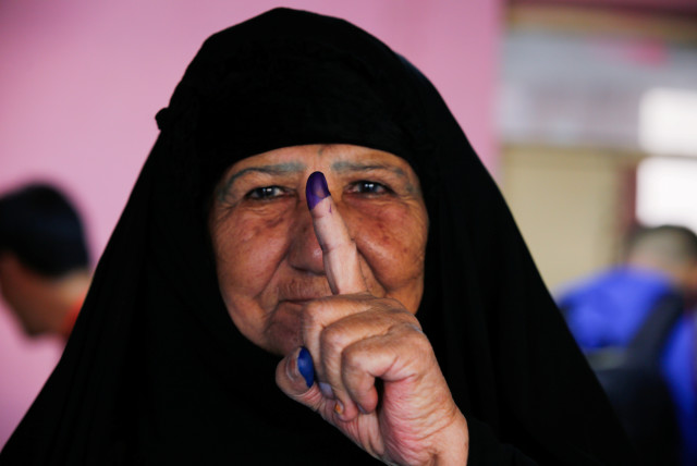 An Iraqi woman shows her ink-stained finger after casting her vote at a polling station during the parliamentary election in the Sadr city district of Baghdad, Iraq October 10, 2021.  (photo credit: REUTERS/WISSAM AL-OKAILI)
