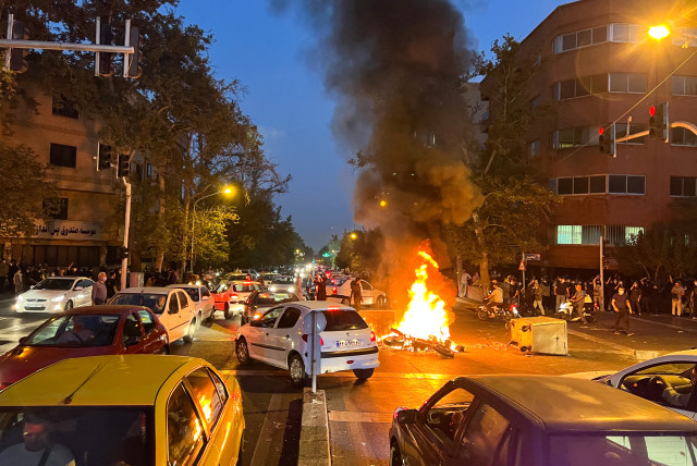A police motorcycle burns during a protest over the death of Mahsa Amini, a woman who died after being arrested by the Islamic republic's "morality police", in Tehran, Iran, September 19, 2022. (photo credit: WANA (WEST ASIA NEWS AGENCY) VIA REUTERS)