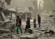 PEOPLE WALK through debris in the center of Afrin, Syria, on March 24, 2018.