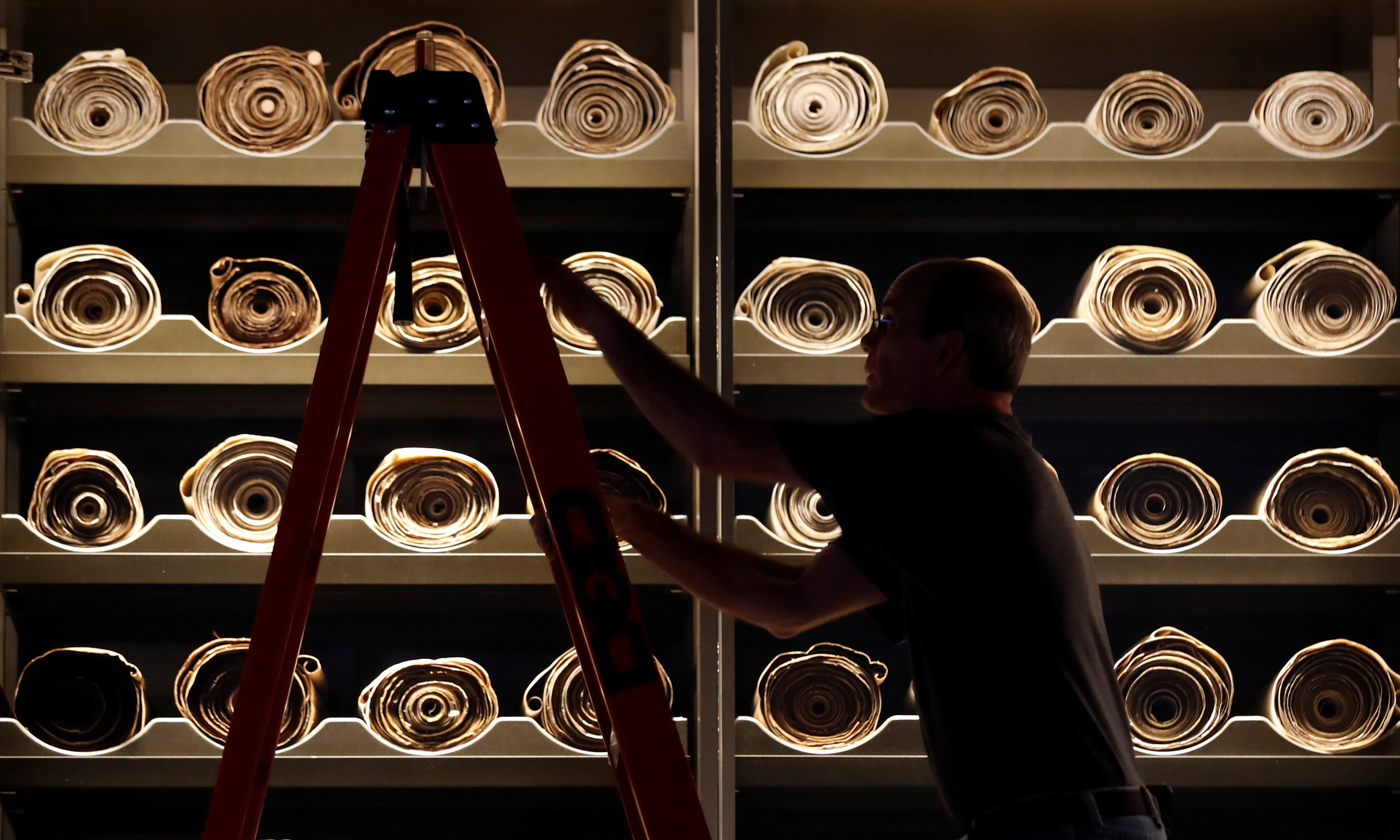 A worker climbs a ladder beside Torah scrolls on display at the Museum of the Bible in Washington, U.S. (Reuters)