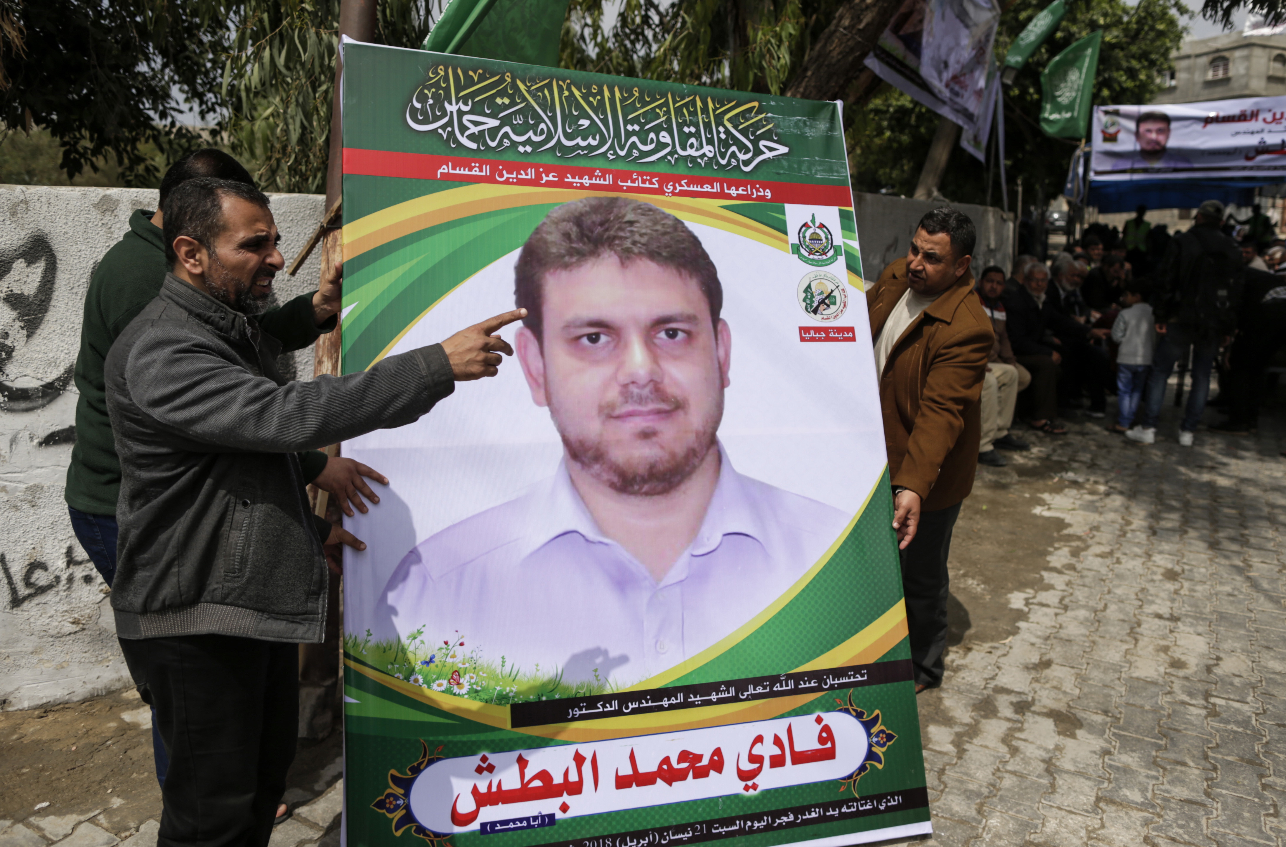 Men holding up a poster portrait of 35-year-old Palestinian professor and Hamas member Fadi Mohammad al-Batsh, who was killed in Malaysia, outside his family's house in Jabalia in the northern Gaza Strip. (MAHMUD HAMS / AFP)