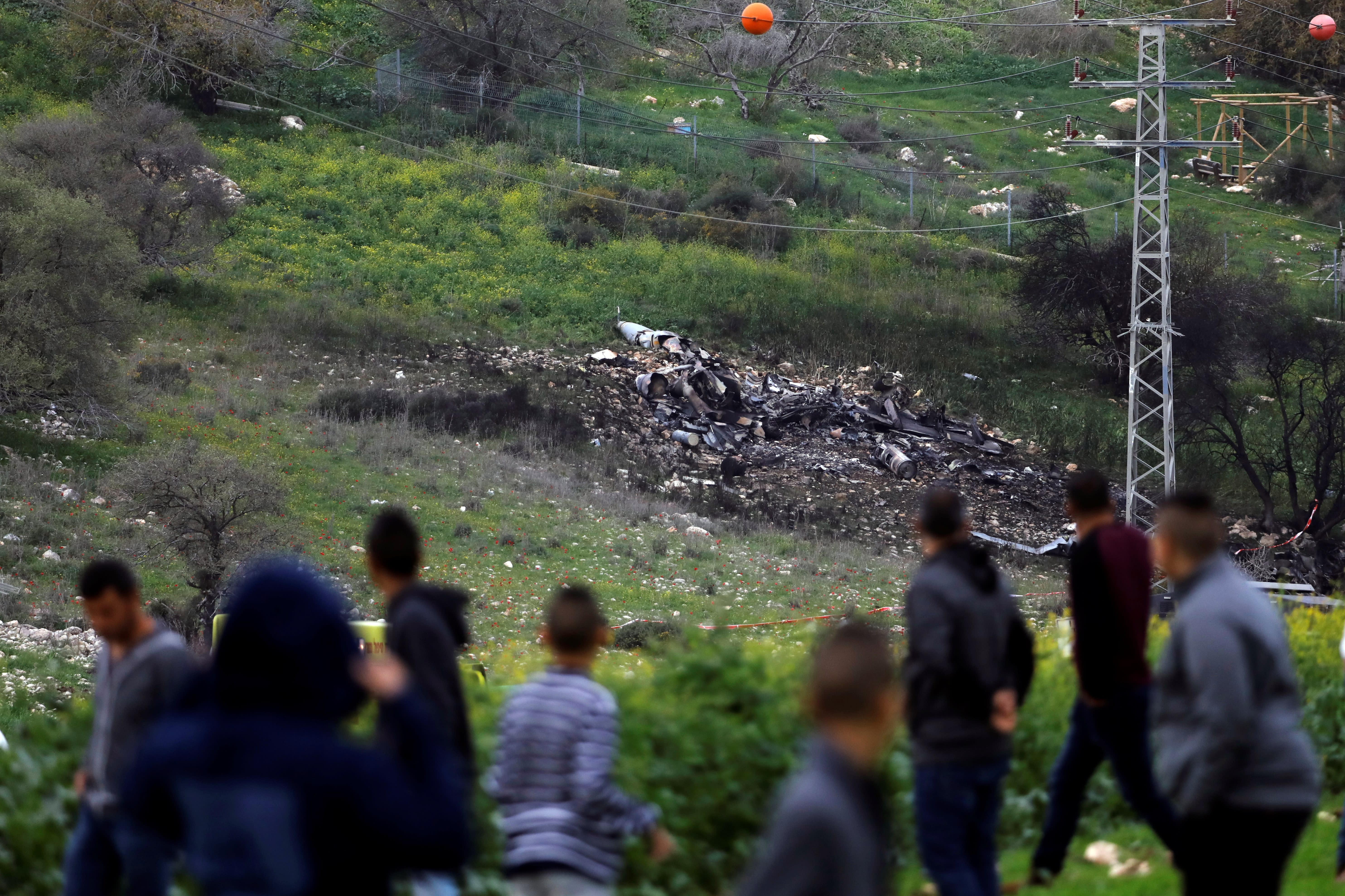 Bystanders look on at the remnants of an Israeli F-16 fighter jet shot down by Syrian forces, February 2018 (RONEN ZVULUN/ REUTERS)