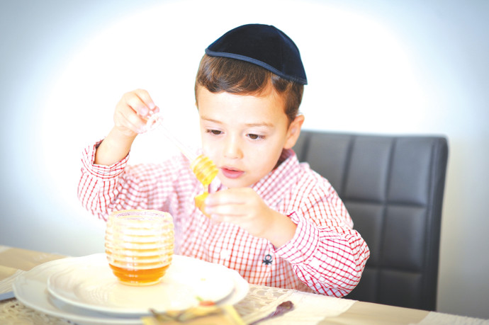 A BOY prepares to eat an apple with honey, as is traditional on Rosh Hashanah.MENDY HECHTMAN/FLASH90