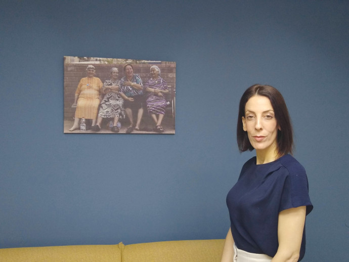Mayor Tal Ohana in her municipality office with the photo of the four Yeroham grandmothers (Credit: ANAV SILVERMAN PERETZ)