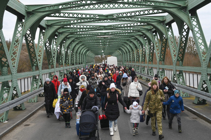 UKRAINIAN REFUGEES cross a bridge at the buffer zone to the border with Poland, Zosin-Ustyluh crossing, western Ukraine, in March. (Daniel Leal/AFP via Getty Images)