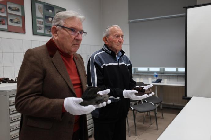 Auschwitz survivors Arie Pinsker (left center) and Bogdan Barnikowski (right center) hold the shoes of child victims of the Nazis in the Conservation Lab in Auschwitz (Credit: Tali Natapov, Neishlos Foundation)