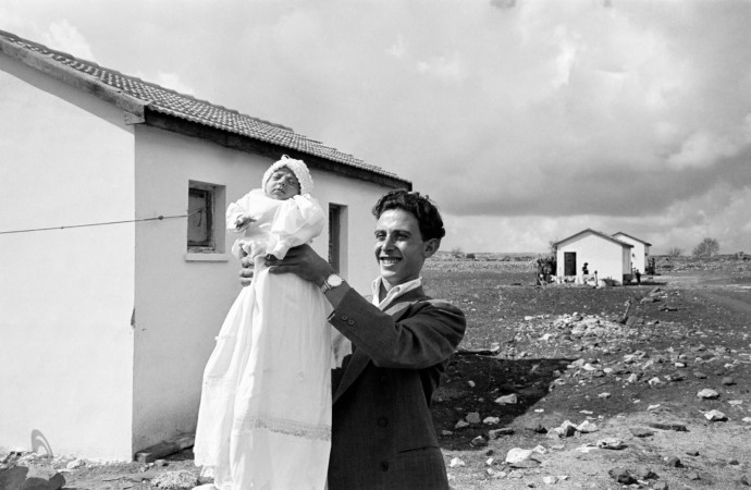 The first child born in the settlement of Alma, in the Upper Galilee. Miriam Trito is held up by her father, Eliezer 1951 (Credit: David Seymour / Magnum Photos, courtesy °CLAIRbyKahn)