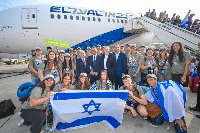 Olim on the 64th Nefesh B’Nefesh charter flight pose with organization’s Co-founders Rabbi Yehoshua Fass and Tony Gelbart; Minister of Aliyah and Integration, Ofir Sofer; and Director-General of the Ministry of Aliyah and Integration, Avichai Kahana. (Credit: SHACHAR AZRAN, YONIT SCHILLER)