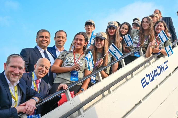 Olim on the 64th Nefesh B’Nefesh charter flight pose with organization’s Co-founders Rabbi Yehoshua Fass and Tony Gelbart; Minister of Aliyah and Integration, Ofir Sofer; and Director-General of the Ministry of Aliyah and Integration, Avichai Kahana. (Credit: Shahar Azran and Yonit Schiller)