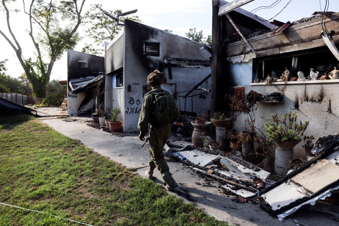 An Israeli soldier walks past the remains of a burnt houses, following a deadly infiltration by Hamas gunmen from the Gaza Strip, in Kibbutz Beeri in southern Israel October 17, 2023 (Credit: REUTERS/Ronen Zvulun)