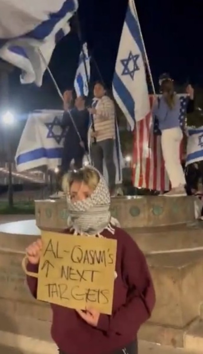 An anti-Israel activist at Columbia University holds a sign that reads “Al-Qasam’s Next Target” pointing at pro-Israel students. Al-Qassam is Hamas’ military (Credit: TWITTER)