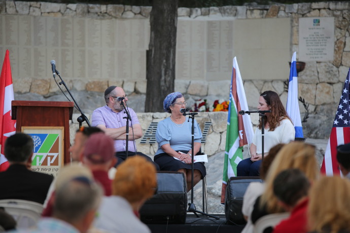 ATARA VOLK-ITZCHAKI, AACI director of projects, in conversation with bereaved parents Lisa Zenilman and Robert Airley. The Memorial Wall is in the background (Credit: COURTESY AACI)