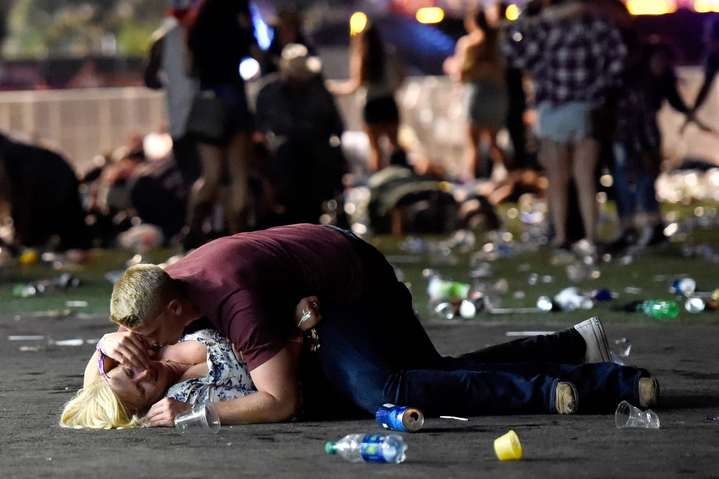 A man lays on top of a woman as people flee a mass shooting in Las Vegas, Nevada (DAVID BECKER / GETTY IMAGES / AFP)