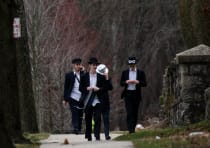 People walk on a street less than a mile away from Young Israel orthodox synagogue in New Rochelle, 
