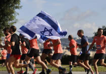   Jerusalem Marathon participants move along the race course, waving a signed Israel flag, March 8, 
