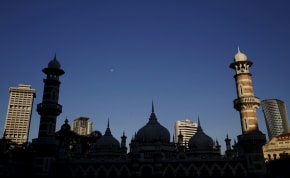 A mosque is silhouetted against city buildings in Kuala Lumpur, Malaysia, January 27, 2016.