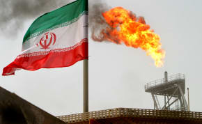 A gas flare on an oil production platform in the Soroush oil fields is seen alongside an Iranian flag in the Persian Gulf, Iran, July 25, 2005
