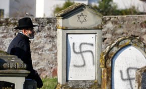  A man walks past graves desecrated with swastikas at the Jewish cemetery in Westhoffen, near Strasbourg, France, December 4, 2019. 