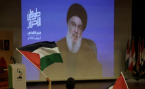   A man holds a Palestinian flag as Lebanon's Hezbollah leader Sayyed Hassan Nasrallah speaks in a pre-recorded message shown on a screen during an event ahead of Al-Quds (Jerusalem) Day on Friday April 5, in Beirut, Lebanon April 3, 2024. 
