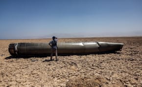  A man stands next to the apparent remains of a ballistic missile, as it lies in the desert near the Dead Sea, following a massive missile and drone attack by Iran on Israel, in southern Israel April 21, 2024 