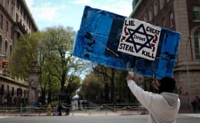 A demonstrator holds a sign across from the Columbia University campus with a student protest encampment in support of Palestinians, during the ongoing conflict between Israel and the Palestinian Islamist group Hamas, in New York City, U.S., April 25, 2024.