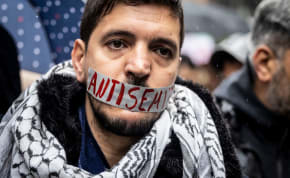  A pro-Palestinian protester wearing a piece of tape over his mouth that reads, "antisemite."