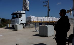  An Israeli soldier stands guard as a truck carrying humanitarian aid makes its way to the Gaza Strip at Erez Crossing in southern Israel, May 5, 2024.