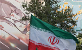  An anti-Israel billboard is seen next to the Iranian flag during a celebration following the IRGC attack on Israel, in Tehran, Iran, April 15, 2024.