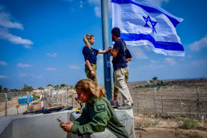  Israeli soldier hangs an Israeli flag in Kibbutz Nir Am, near the Israeli border with the Gaza Stri