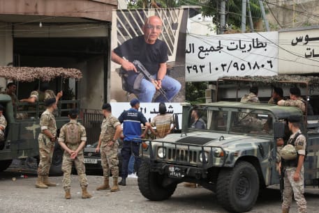  Lebanese army members stand near a poster of Fadi Bejjani who died during exchange of fire at the area where a truck was overturned the previous night, in the town of Kahaleh, Lebanon August 10, 2023.