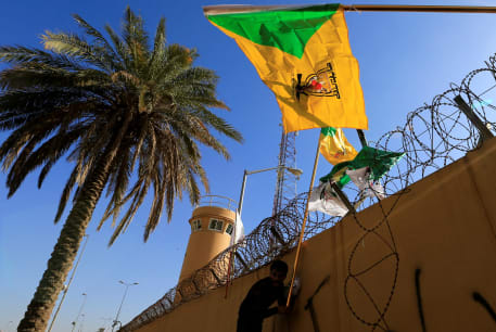  A member of Hashd al-Shaabi (paramilitary forces) holds a flag of Kataib Hezbollah militia group during a protest to condemn air strikes on their bases, outside the main gate of the U.S. Embassy in Baghdad, Iraq December 31, 2019. 