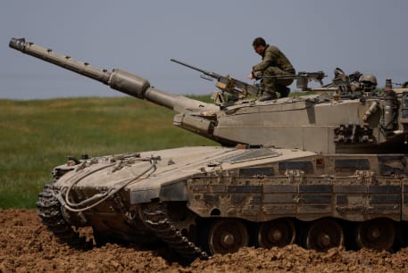 Israeli soldier unloads a weapon on top of a tank Israel's border with Gaza, March 30, 2024