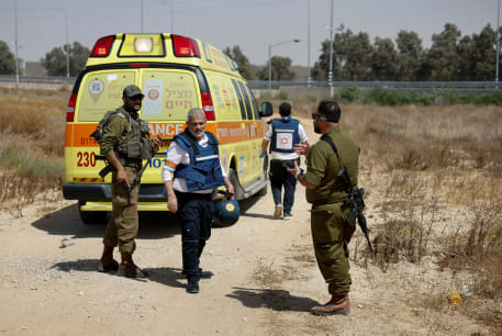 An Israeli medic walks near soldiers and an ambulance after Hamas claimed responsibility for an attack on Kerem Shalom crossing, May 5, 2024.
